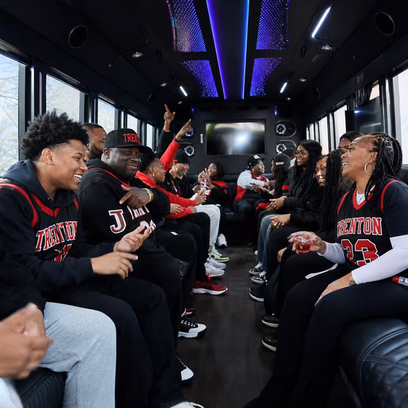 Group boarding a white charter bus for Sporting Event Transportation transportation in Trenton